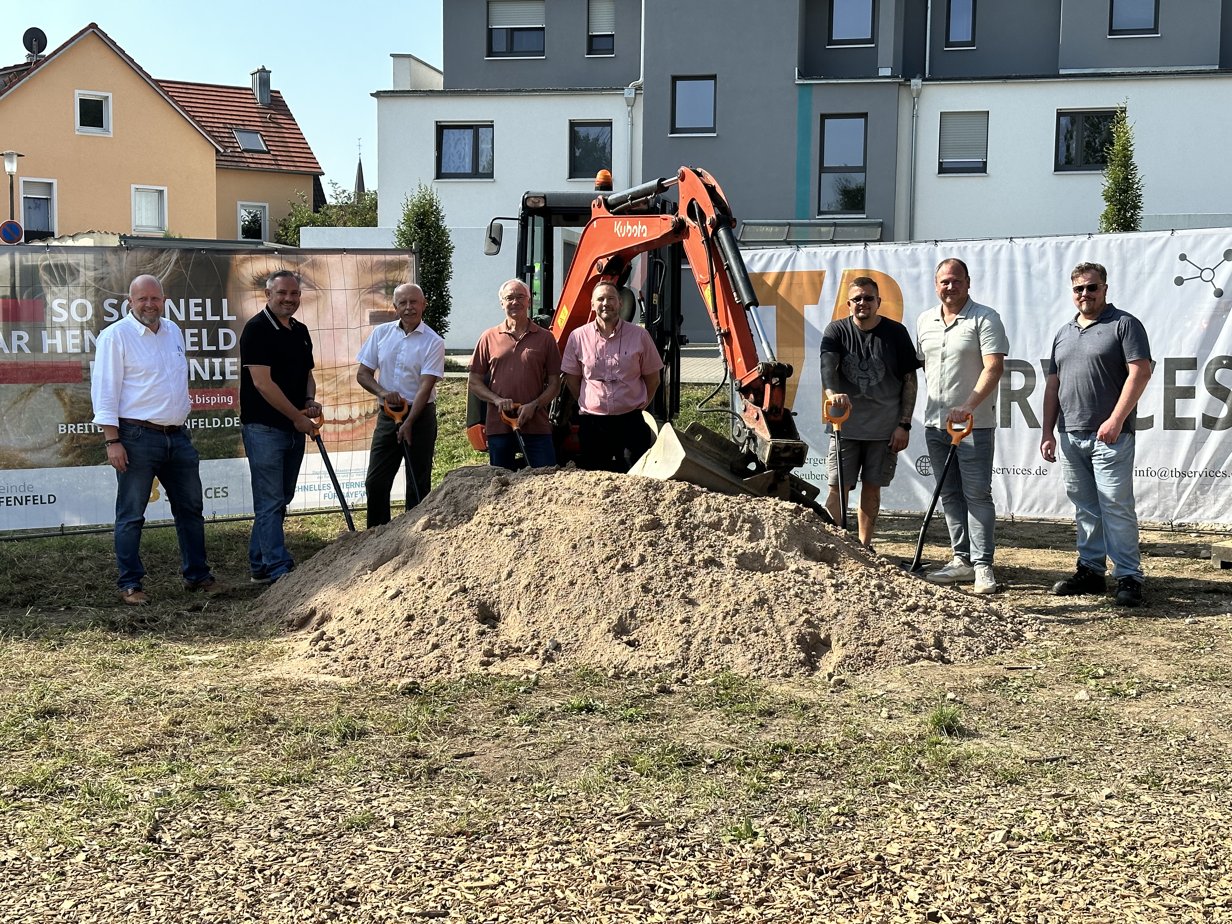 Vertragsunterzeichnung für den Glasfaserausbau in Henfenfeld: Bürgermeister Markus Gleißenberg und Johannes Bisping unterzeichnen die Kooperationsvereinbarung, begleitet von weiteren Projektbeteiligten vor dem Bisping & Bisping Banner.